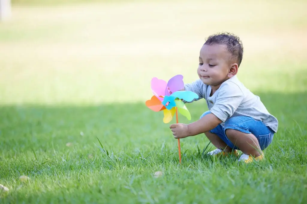 1 year old child playing with multicolored pinwheel