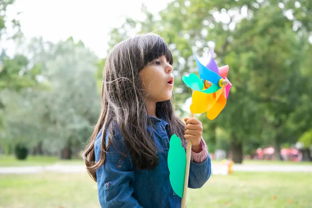 Female Child blowing on a multicolored pinwheel